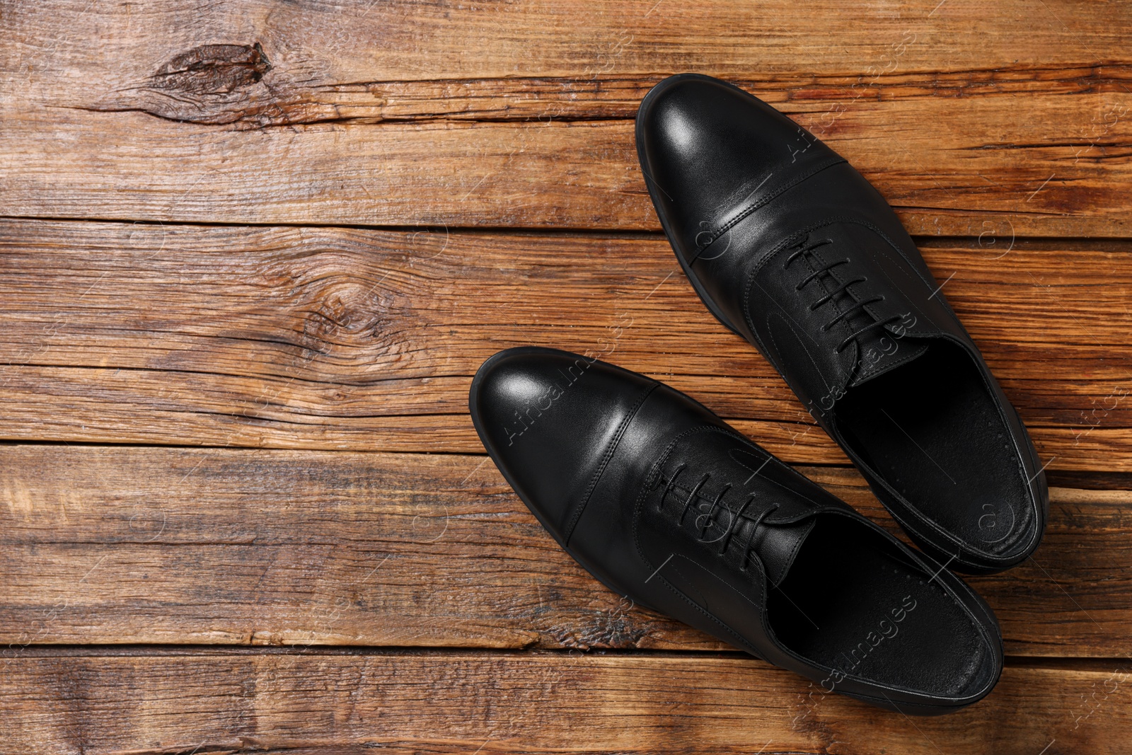 Photo of Pair of black leather men shoes on wooden background, top view. Space for text