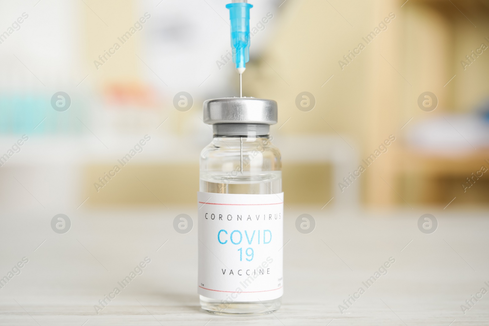 Photo of Filling syringe with vaccine against Covid-19 on white table indoors