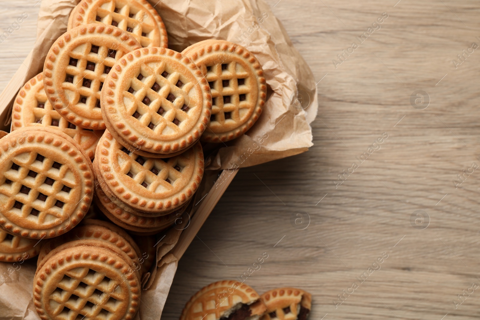 Photo of Tasty sandwich cookies with cream on wooden table, flat lay. Space for text