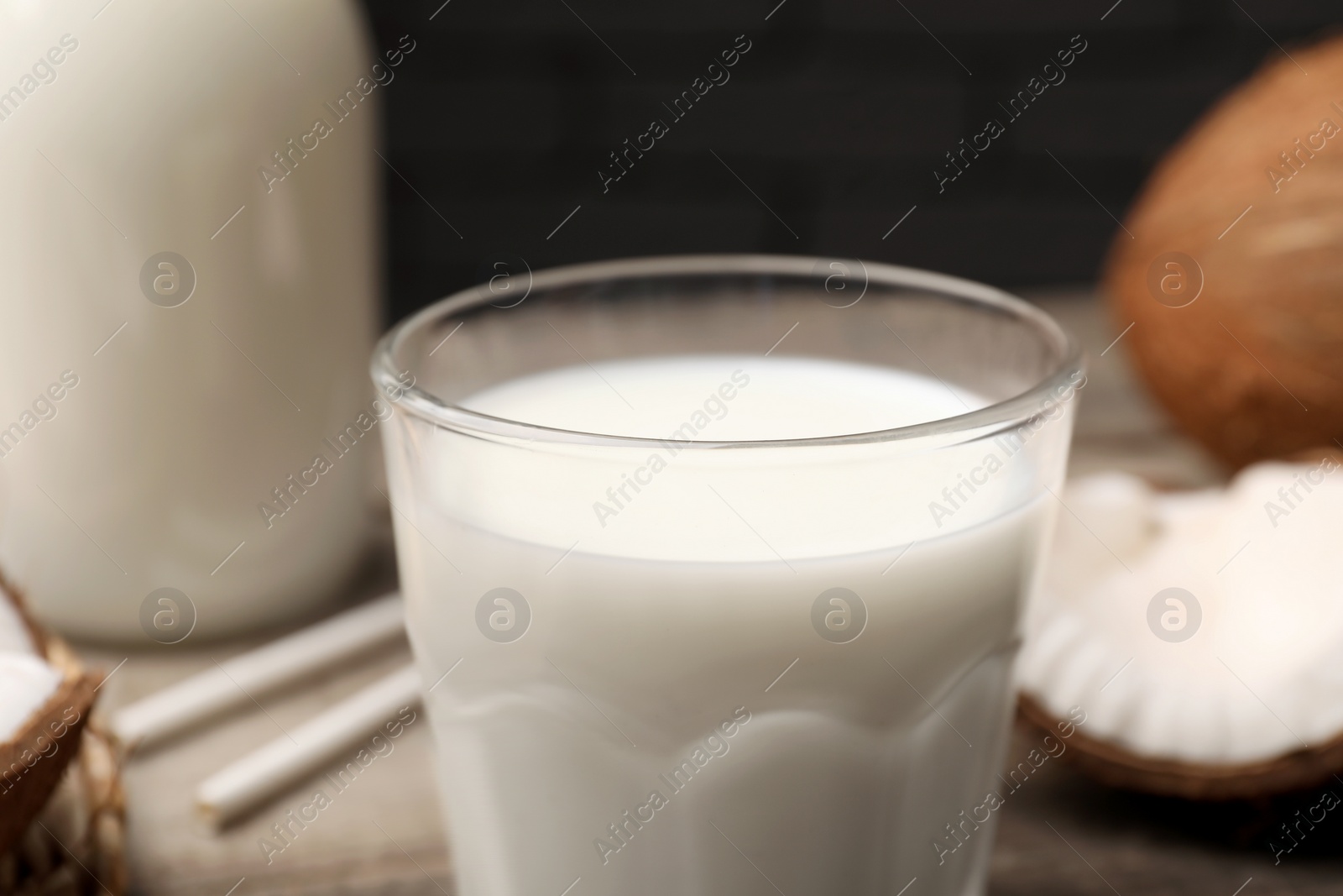 Photo of Glass of fresh coconut milk on table, closeup