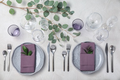 Festive table setting with plates, cutlery and napkins on light background, flat lay