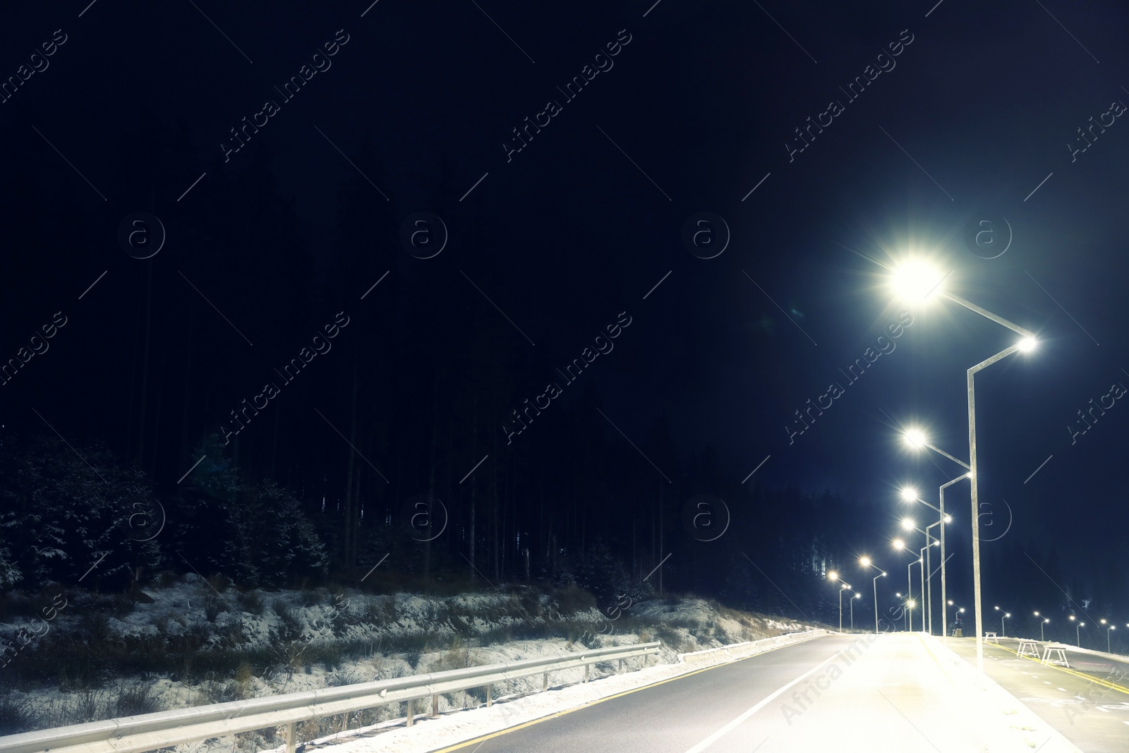 Photo of Night landscape with illuminated road and forest in winter