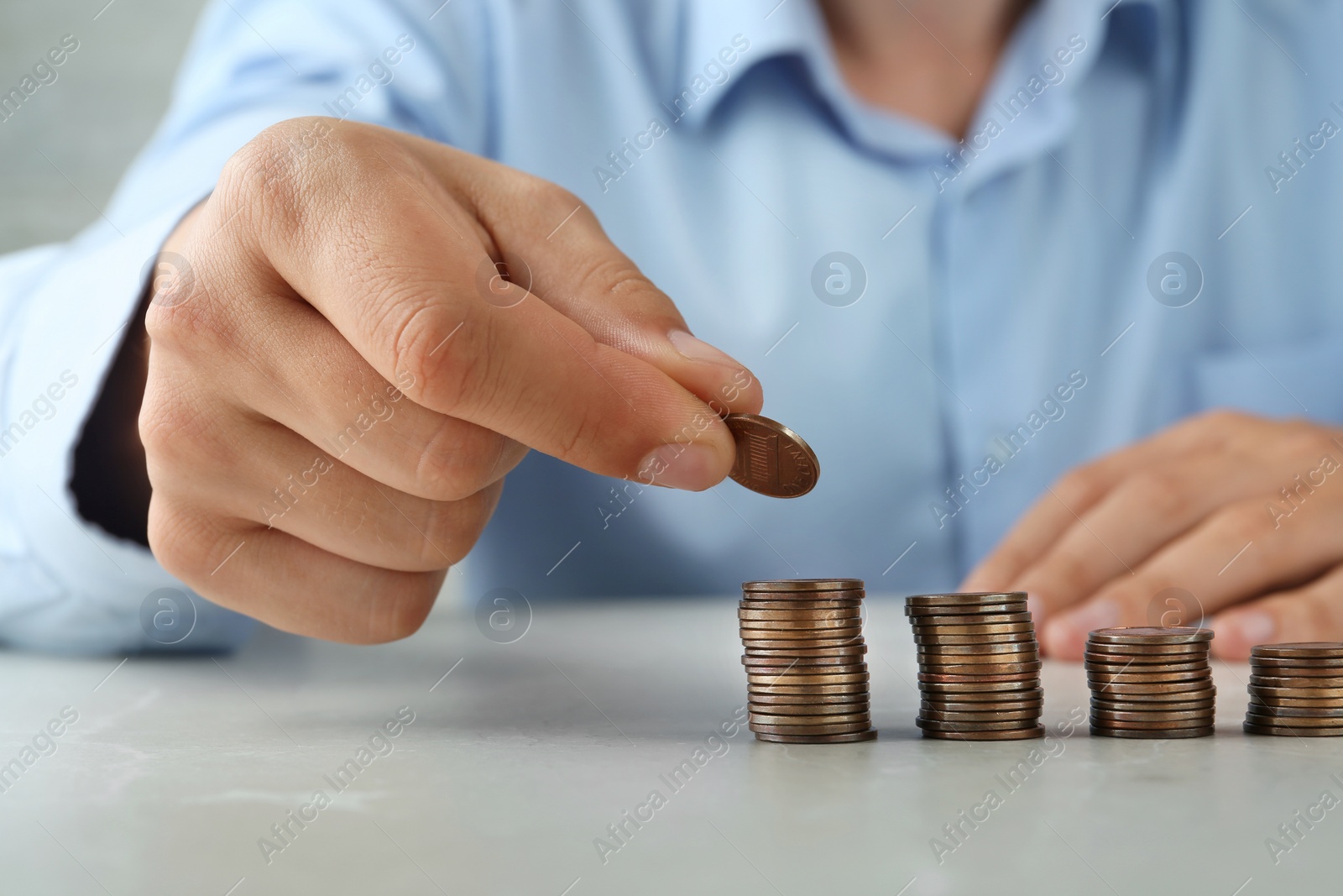 Photo of Man stacking coins on grey stone table, closeup view