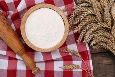 Photo of Ears of wheat and flour on wooden table, flat lay