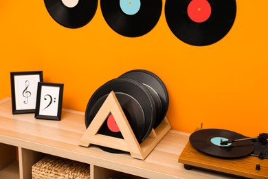 Photo of Vinyl records and player on wooden cabinet near orange wall