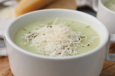 Photo of Delicious cream soup with parmesan cheese in bowl on table, closeup