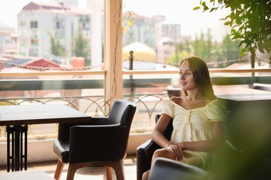 Photo of Beautiful young woman sitting on indoor terrace in cafe