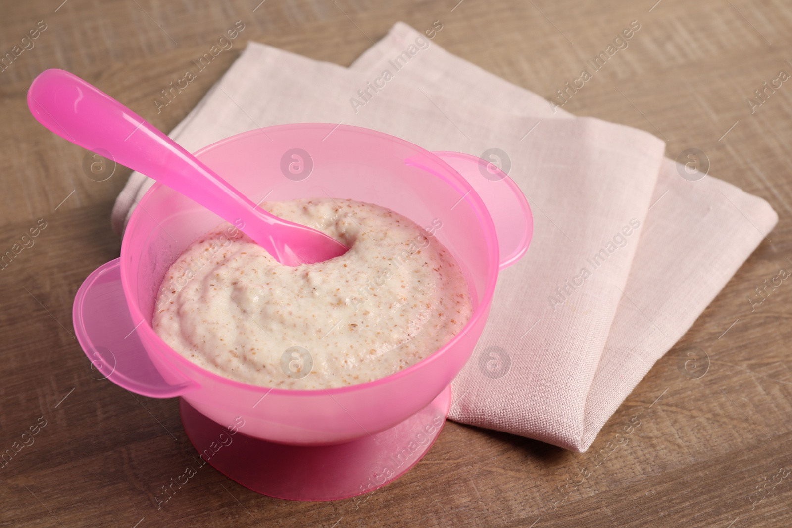 Photo of Baby food. Puree and spoon in bowl on wooden table