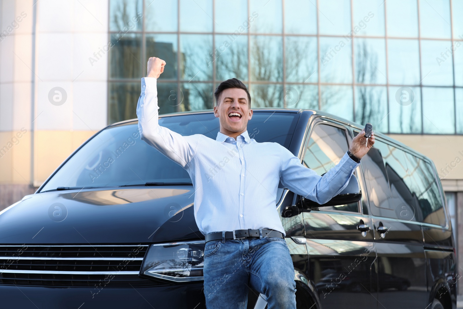 Photo of Excited man with key near car on city street. Buying new auto