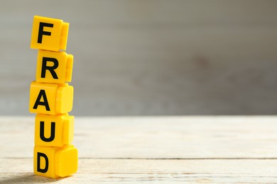 Photo of Word Fraud of yellow cubes with letters on white wooden background. Space for text