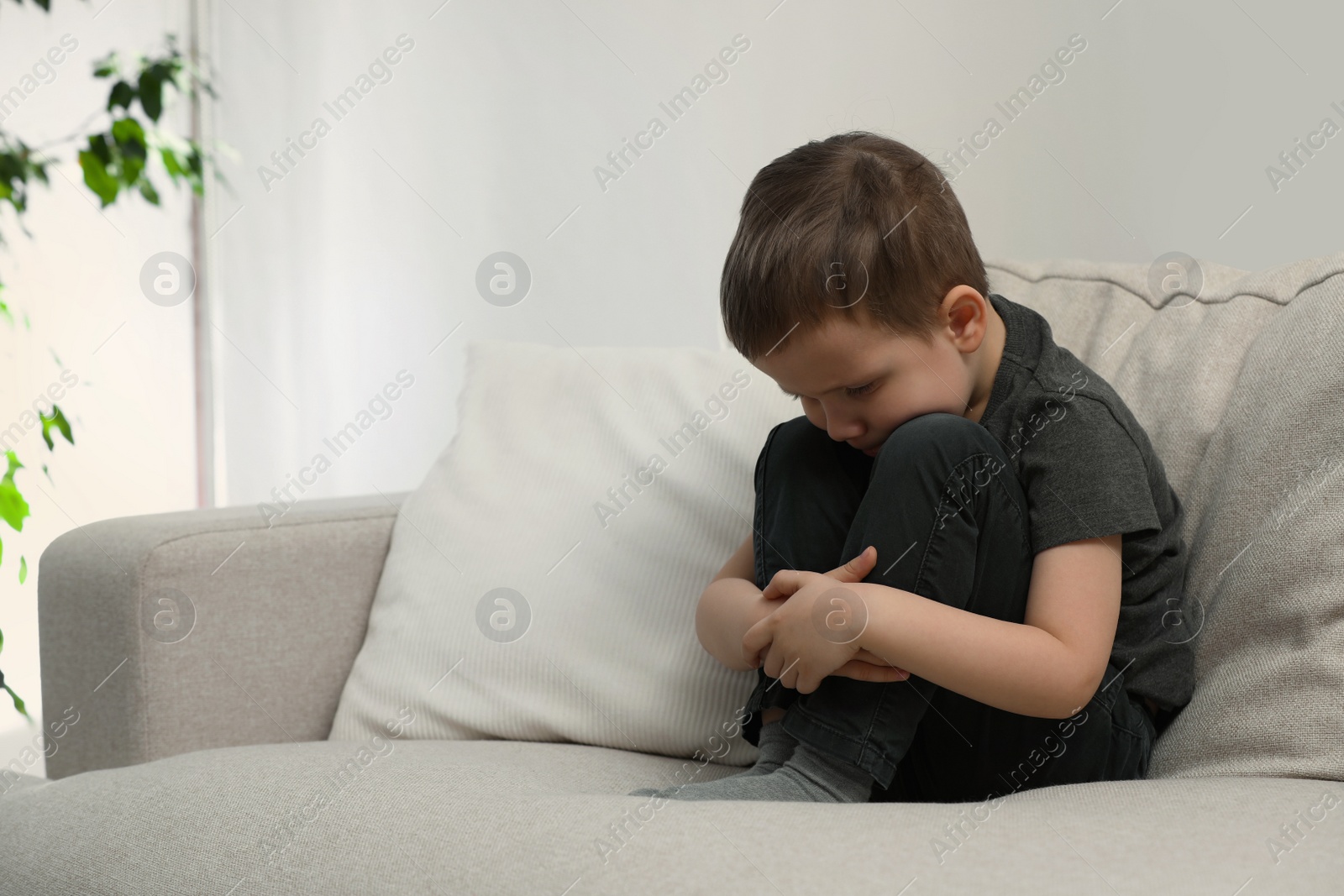 Photo of Sad little boy on sofa at home