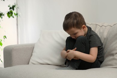 Photo of Sad little boy on sofa at home