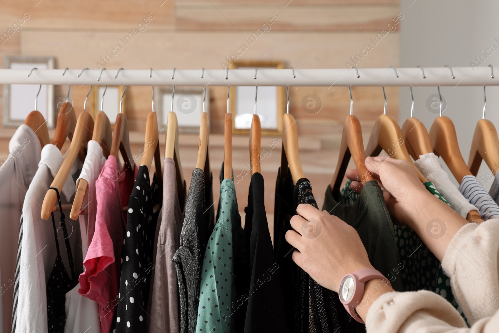 Photo of Woman choosing clothes from wardrobe rack, closeup