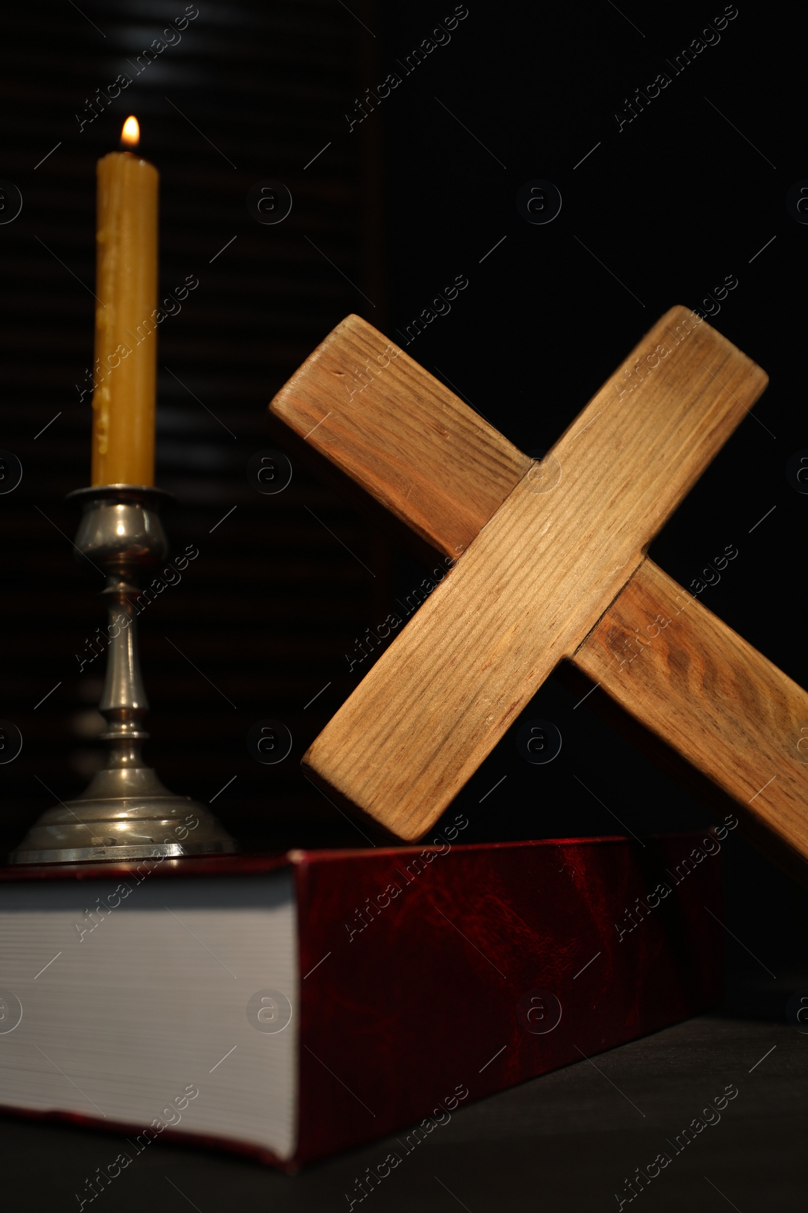 Photo of Church candle, Bible and wooden cross on table