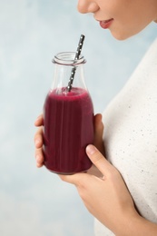 Photo of Woman with bottle of beet smoothie on light background, closeup