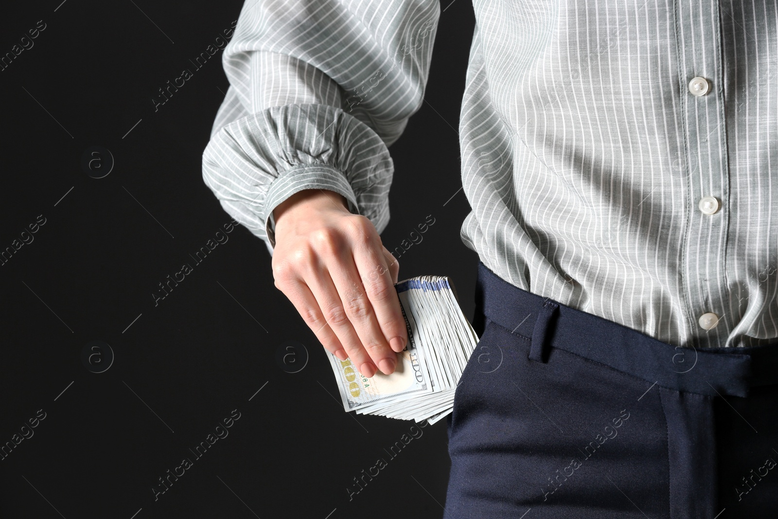 Photo of Woman putting bribe into pocket on black background, closeup