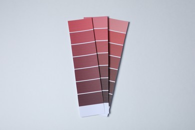 Photo of Color paint chips of red shades on light background, top view