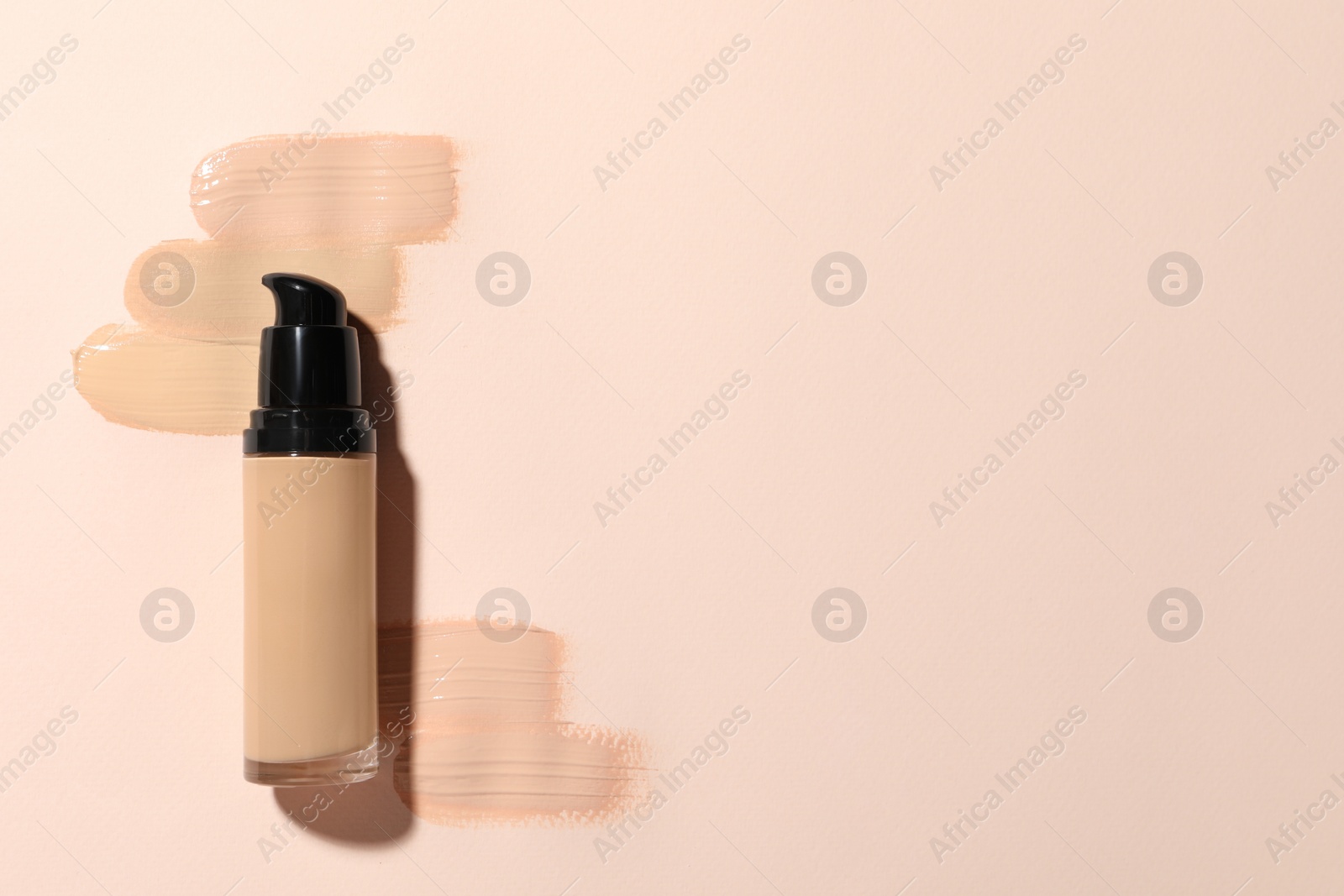 Photo of Liquid foundation and swatches on beige background, top view. Space for text