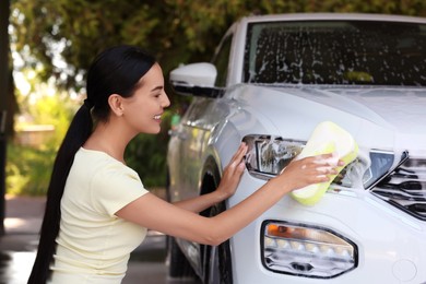 Photo of Woman washing auto with sponge at outdoor car wash