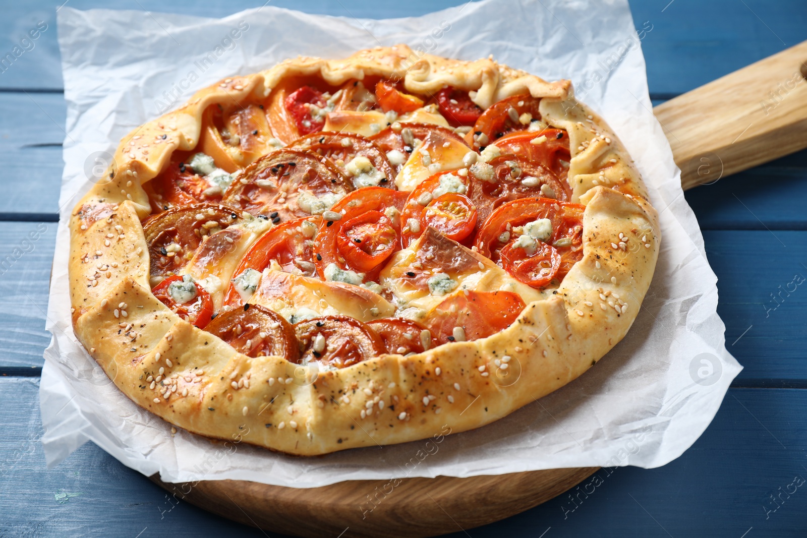 Photo of Tasty galette with tomato and cheese (Caprese galette) on blue wooden table, closeup