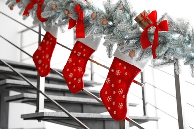 Photo of Santa stockings and garland on railing indoors. Christmas decor idea