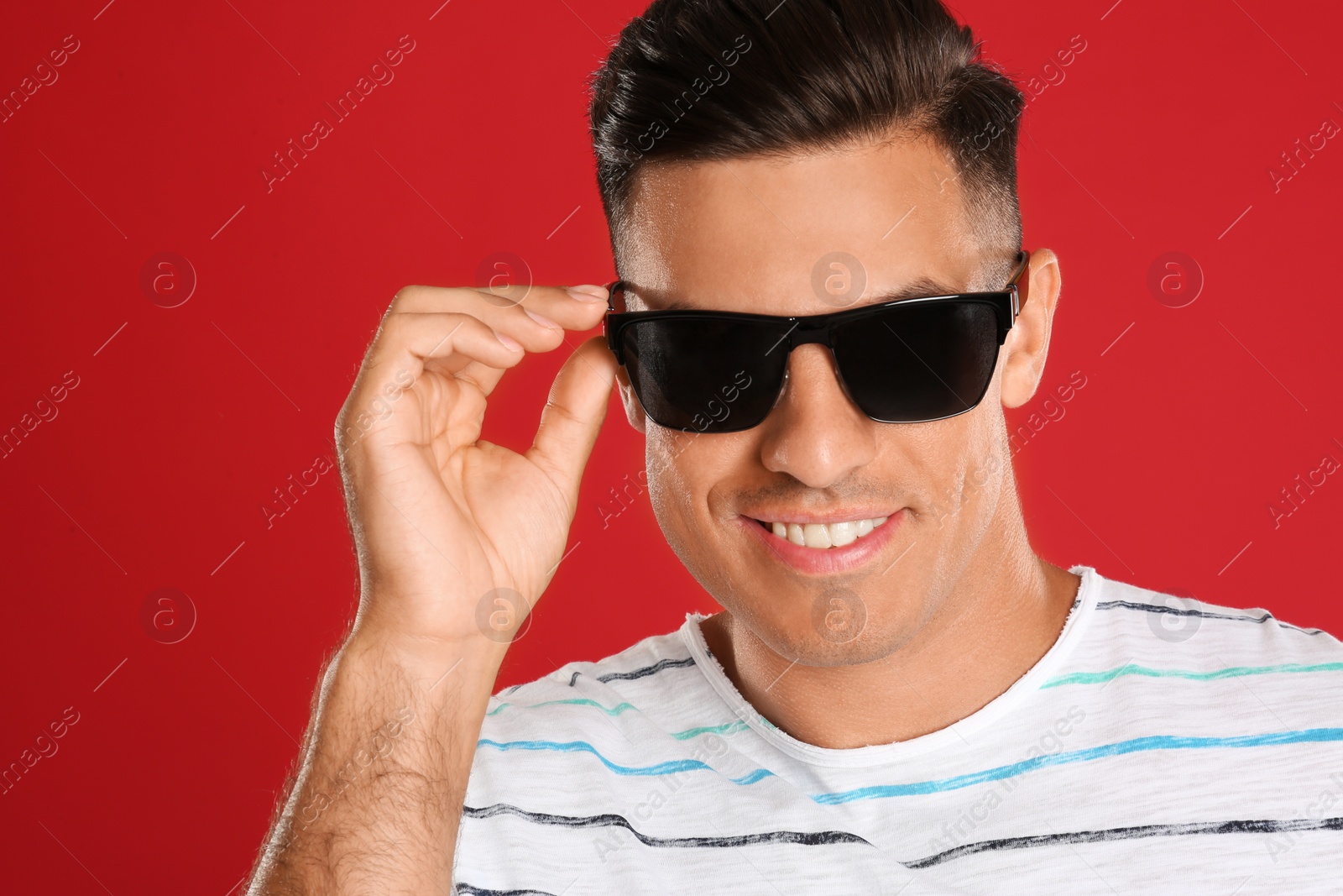 Photo of Handsome man wearing sunglasses on red background, closeup