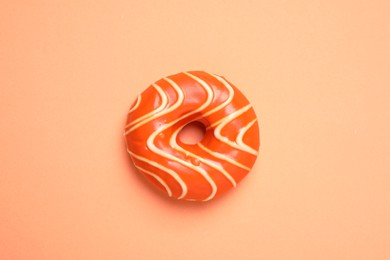 Delicious glazed donut on orange background, top view