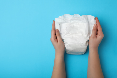 Photo of Woman with diaper on light blue background, closeup. Space for text