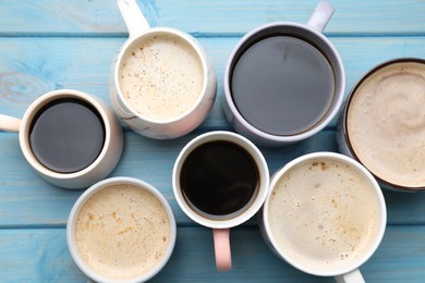 Many cups of different coffee drinks on light blue wooden table, flat lay