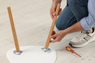 Photo of Man assembling table on floor, closeup view