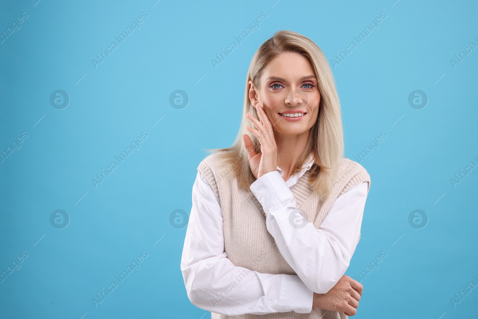 Photo of Portrait of smiling middle aged woman on light blue background. Space for text