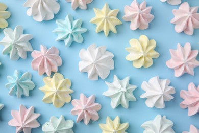 Photo of Tasty meringue cookies on light blue background, flat lay