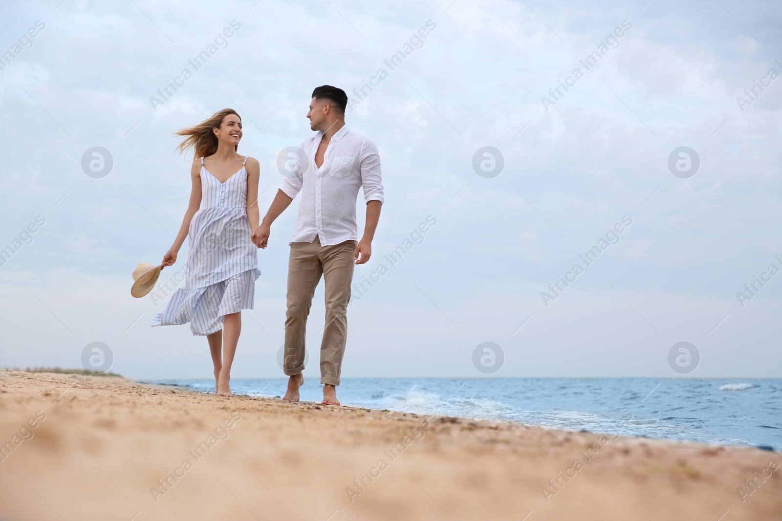 Photo of Happy couple having romantic walk on beach. Space for text