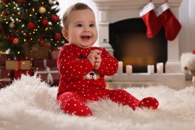 Photo of Baby in bright Christmas pajamas on floor at home