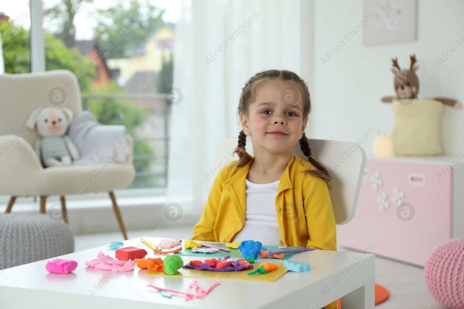 Photo of Portrait of little girl at table with play dough in kindergarten