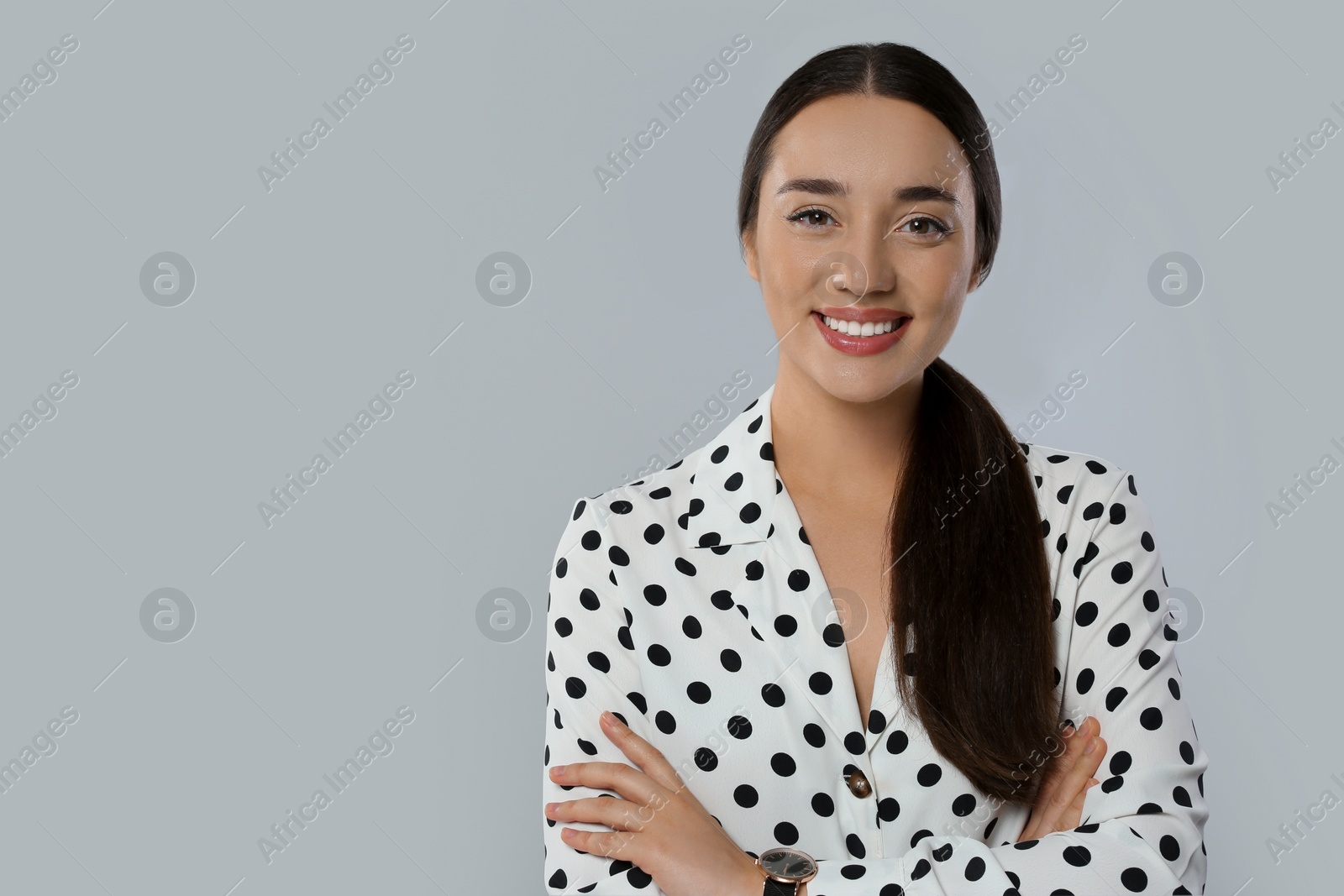 Photo of Portrait of beautiful young woman in polka dot blouse on light grey background. Space for text