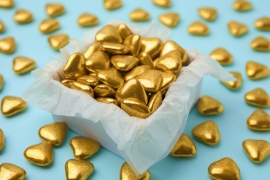 Photo of Box and delicious heart shaped candies on light blue background, closeup