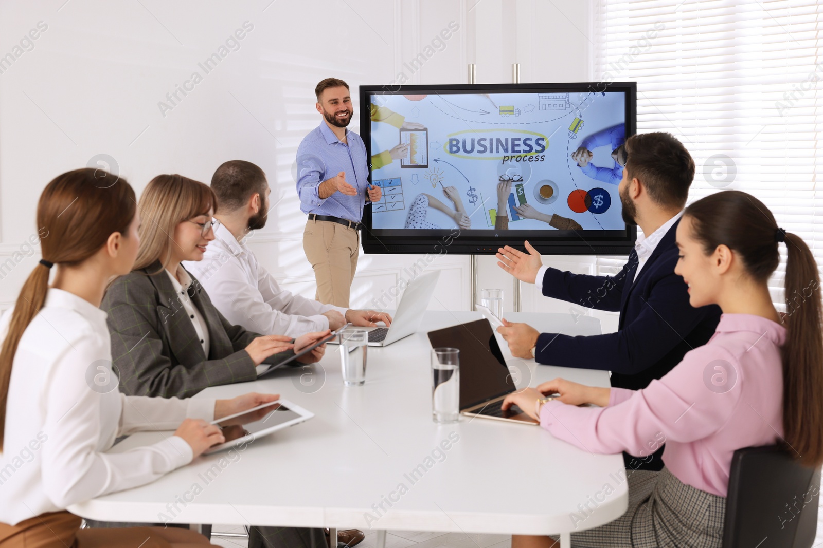 Photo of Business trainer near interactive board in meeting room during presentation