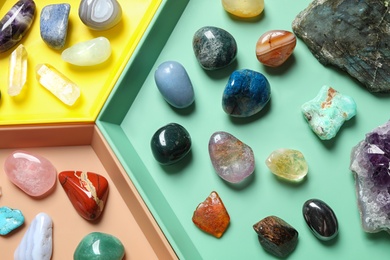 Plastic tray with different beautiful gemstones as background, top view