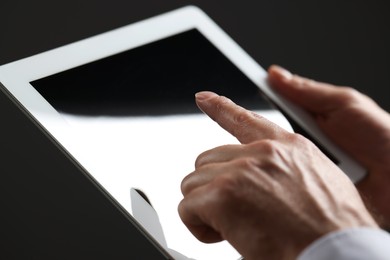 Closeup view of man using new tablet on black background