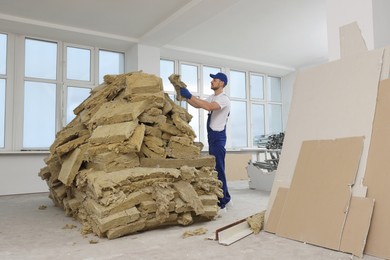 Photo of Construction worker with used glass wool in room prepared for renovation