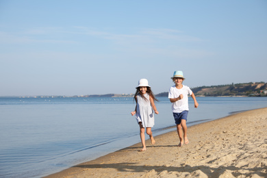 Photo of Cute little children running at sandy beach on sunny day