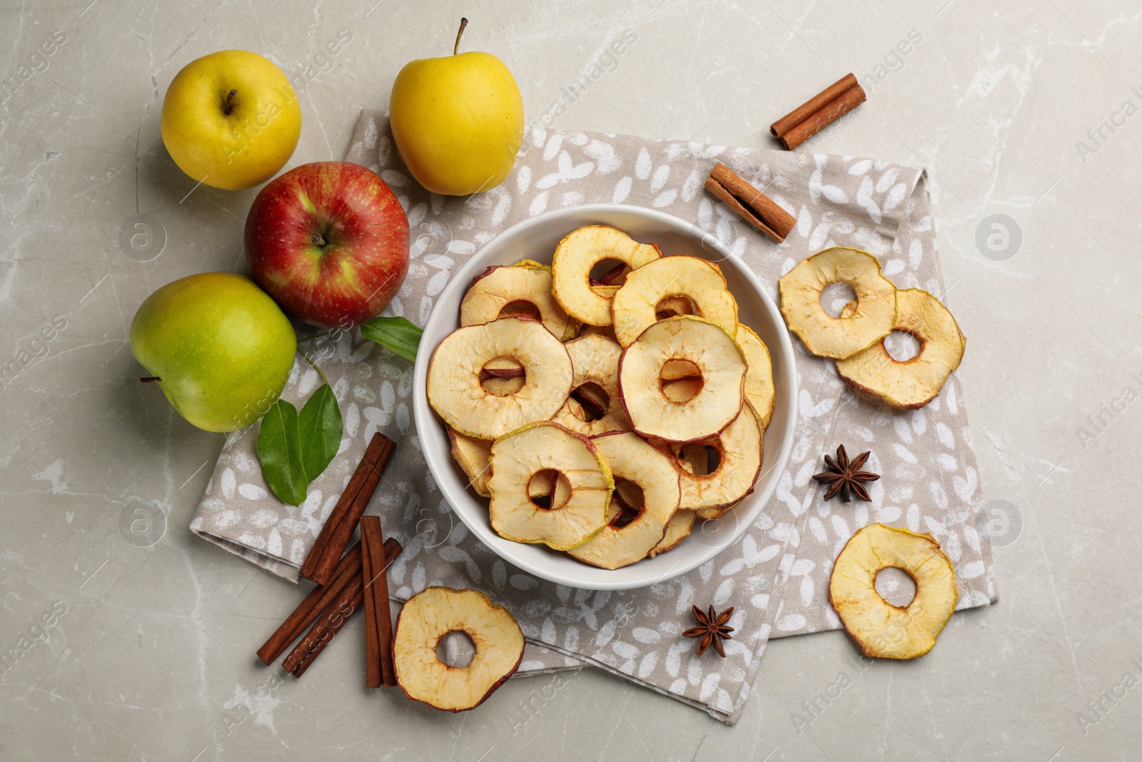 Photo of Delicious apple chips, fresh fruits, anise and cinnamon on light grey table, flat lay