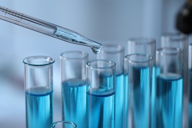 Photo of Dripping liquid from pipette into test tube in laboratory, closeup