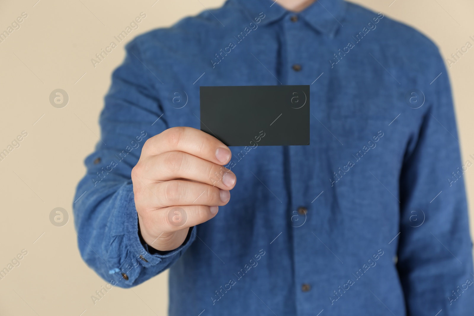 Photo of Man holding black business card on beige background, closeup