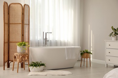 Photo of White tub near window in light room. Interior design