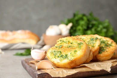 Photo of Slices of toasted bread with garlic and herbs on light table against grey background