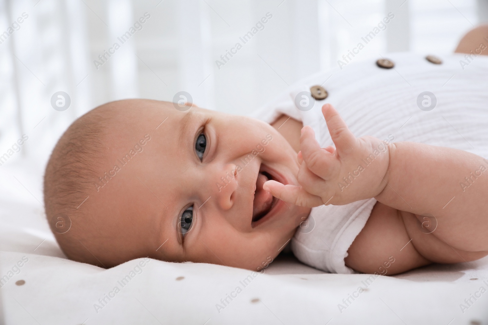 Photo of Cute little baby lying on bed at home, closeup