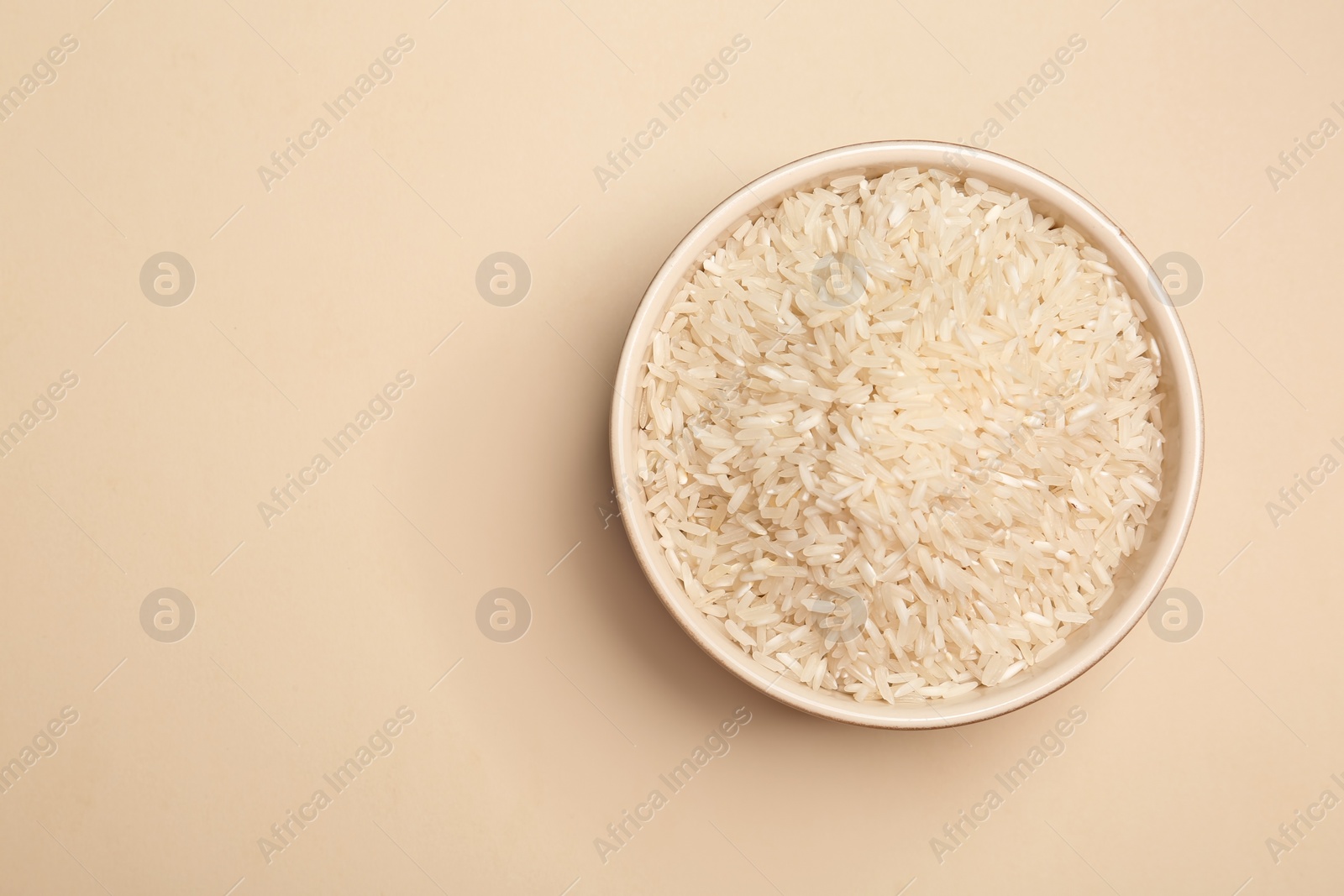 Photo of Long grain rice in bowl on light background, top view with space for text