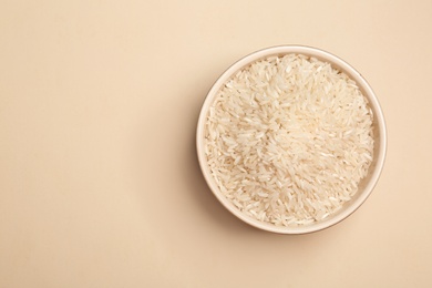 Long grain rice in bowl on light background, top view with space for text